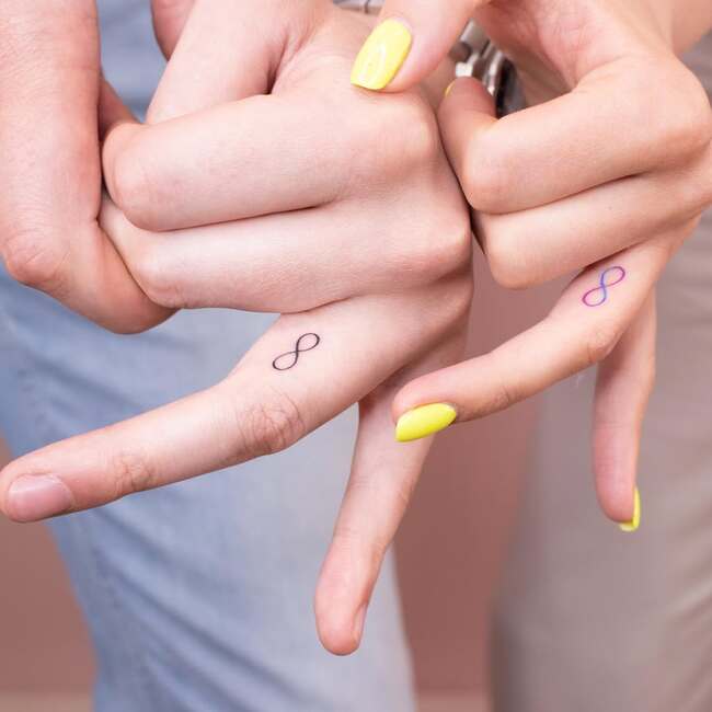 Mini tattoo w postaci symbolu nieskończoności na palcach serdecznych pary