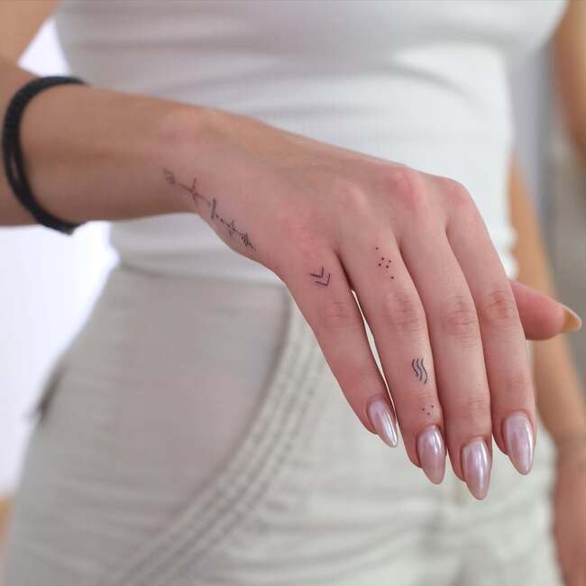 Lakoniczne geometryczne tatuaże na palcach i dłoni dziewczyny z perłowym manicure