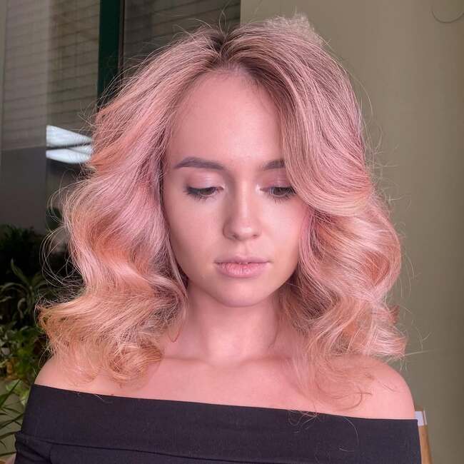 Voluminöse Frisur für mittlere rosa Haare mit sanften Locken und Pony