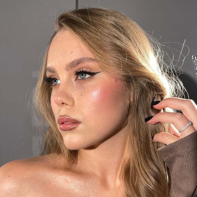 Nude makeup with blush and striking cat-eye liner