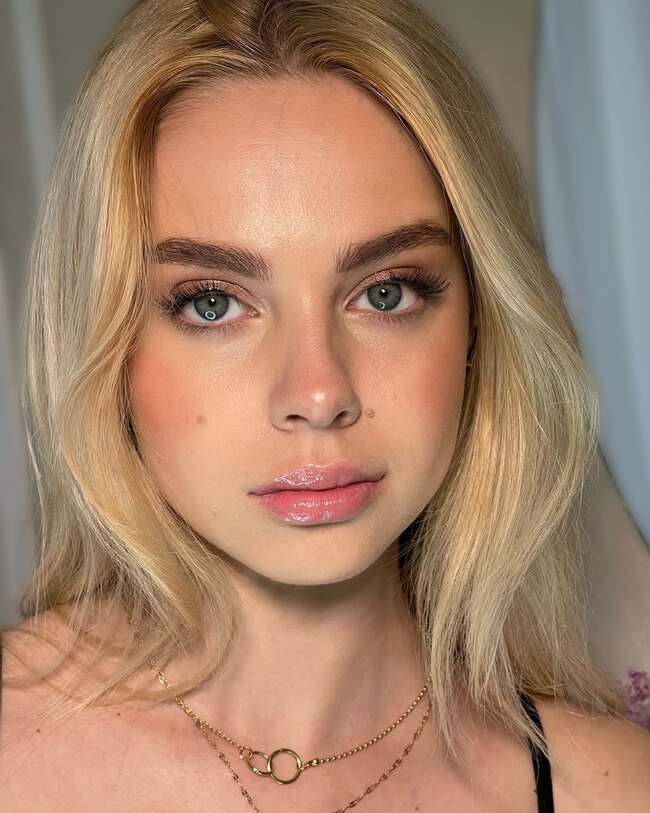 Fresh nude makeup emphasizing glossy lips and fluffy lashes