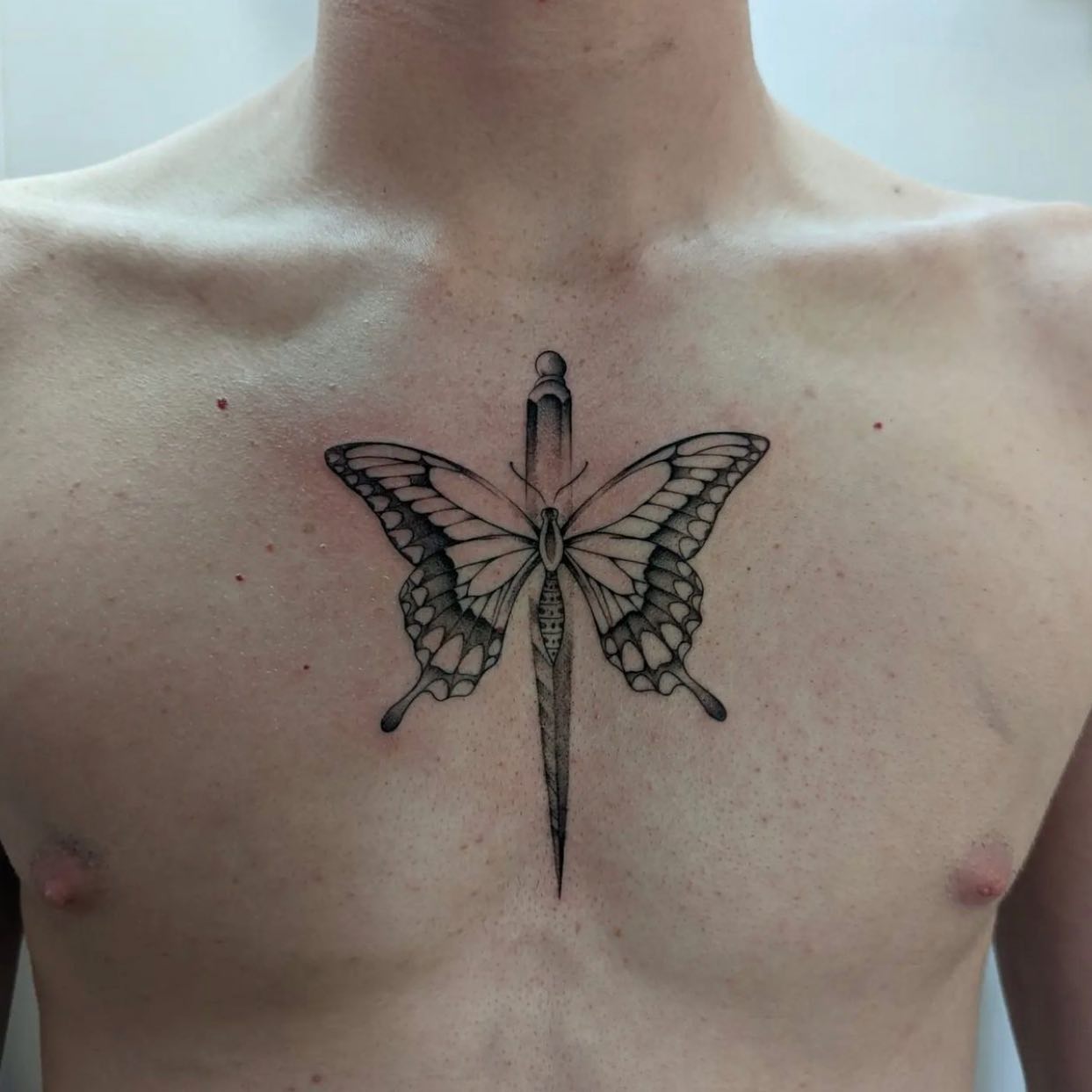 Sternum-Dolch und Schmetterlings-Tattoo