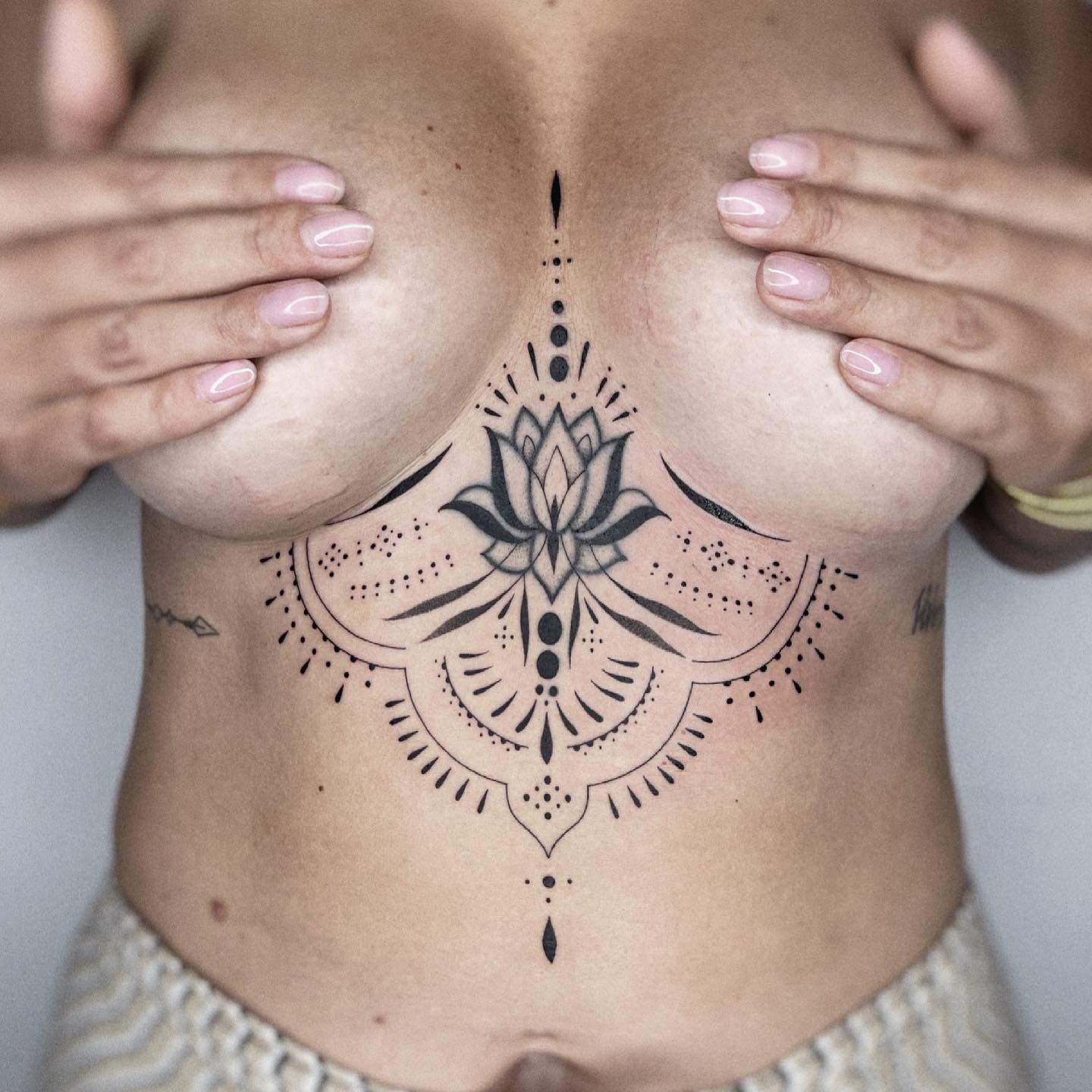 Mandala-Tattoo mit Lotusblume und Spitze im Brustbein