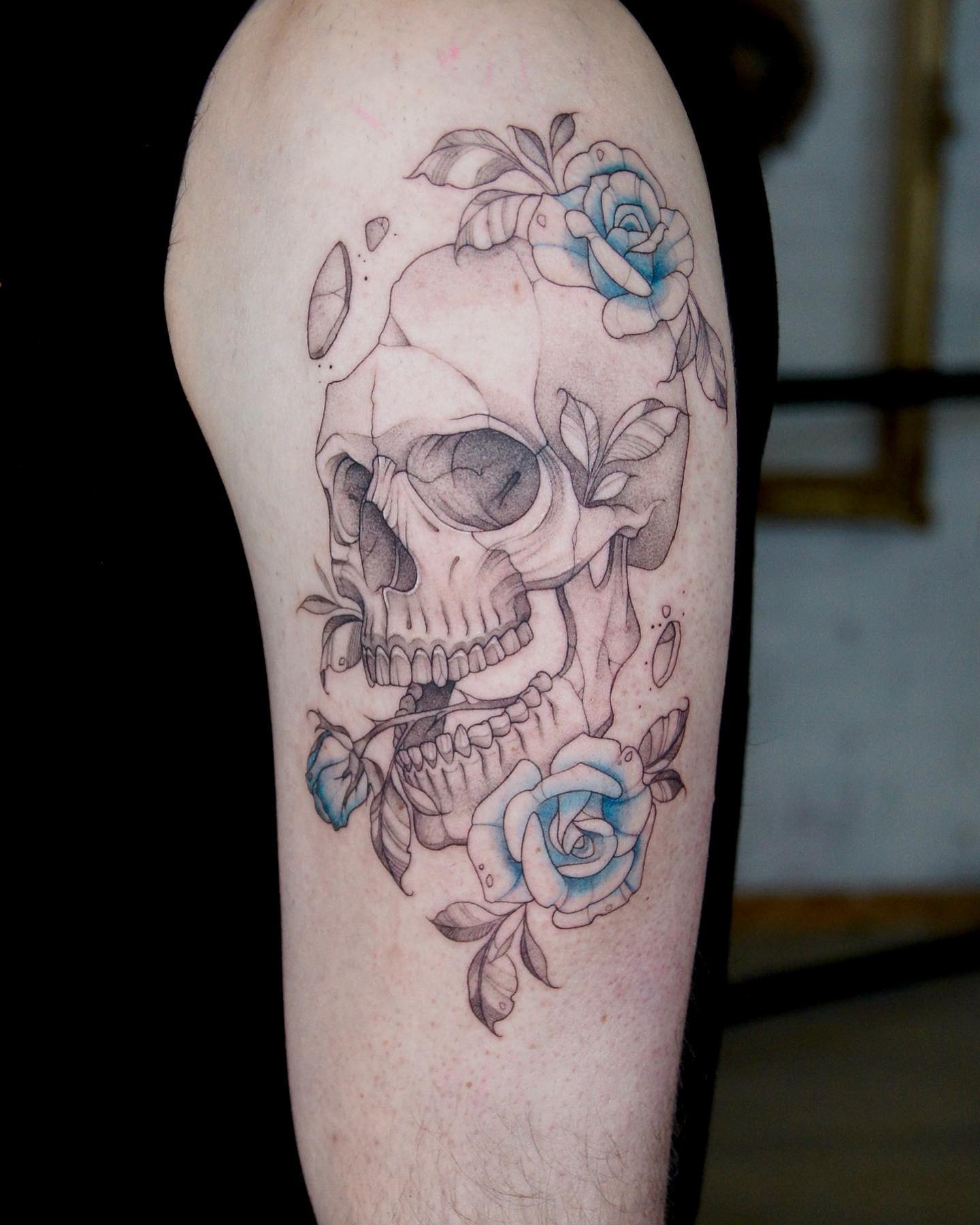 Tatuaż na ramieniu z czaszką i różami