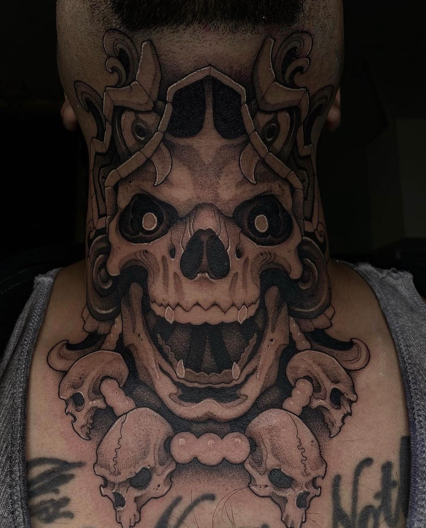 Czarny tatuaż na szyi czaszki