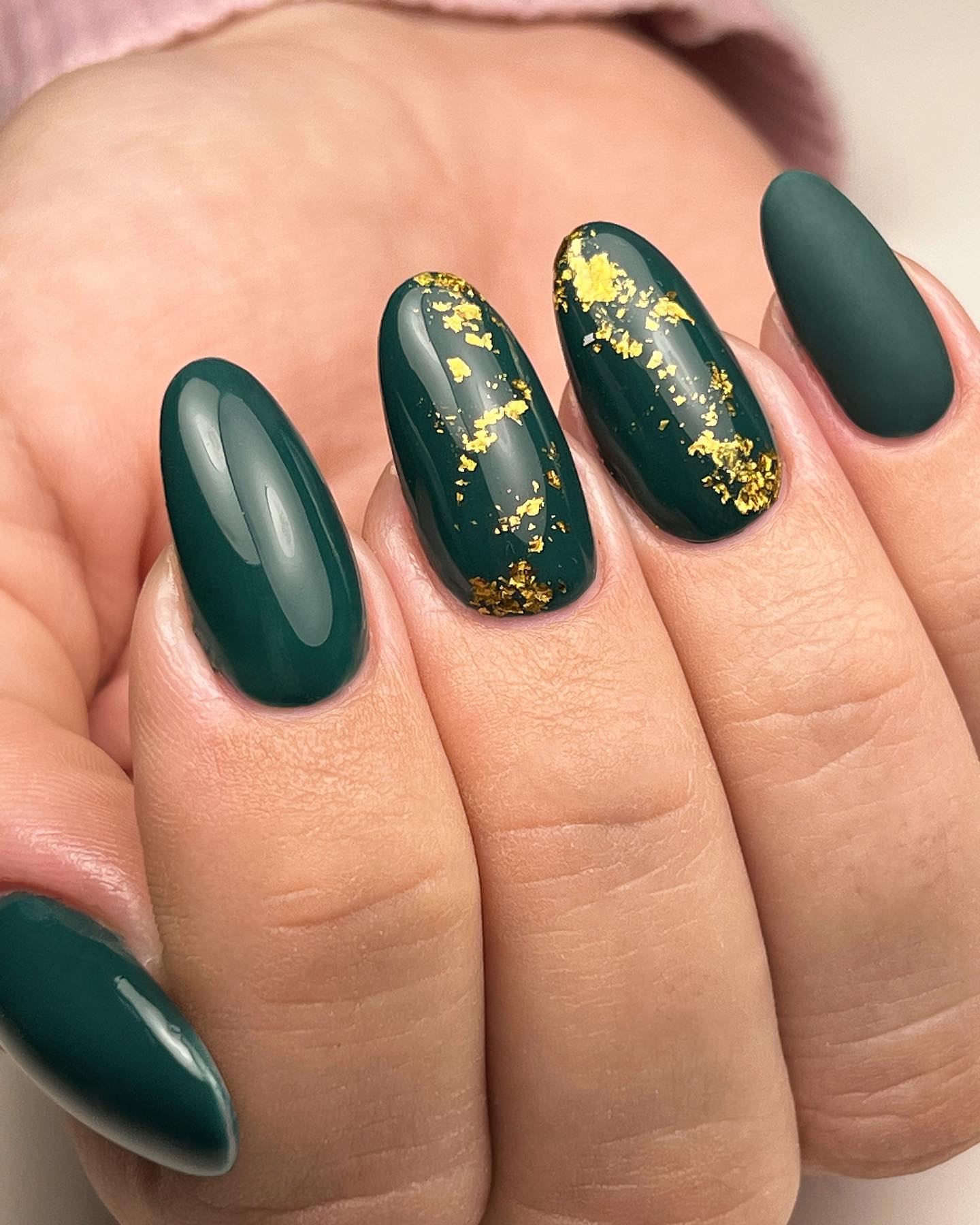 Zbliżenie leśnych zielonych paznokci z ozdobami ze złotej folii