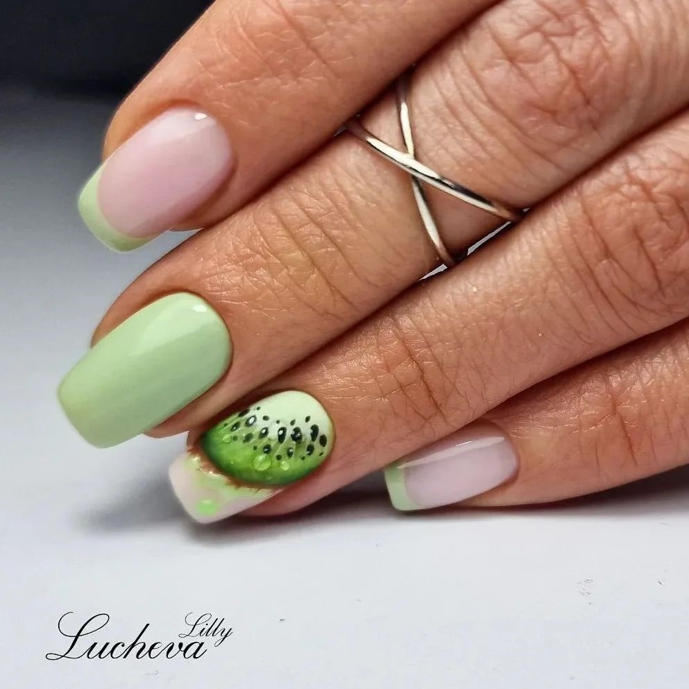 Eine Nahaufnahme grüner Nägel mit Pastellgrund und Fruchtmalerei