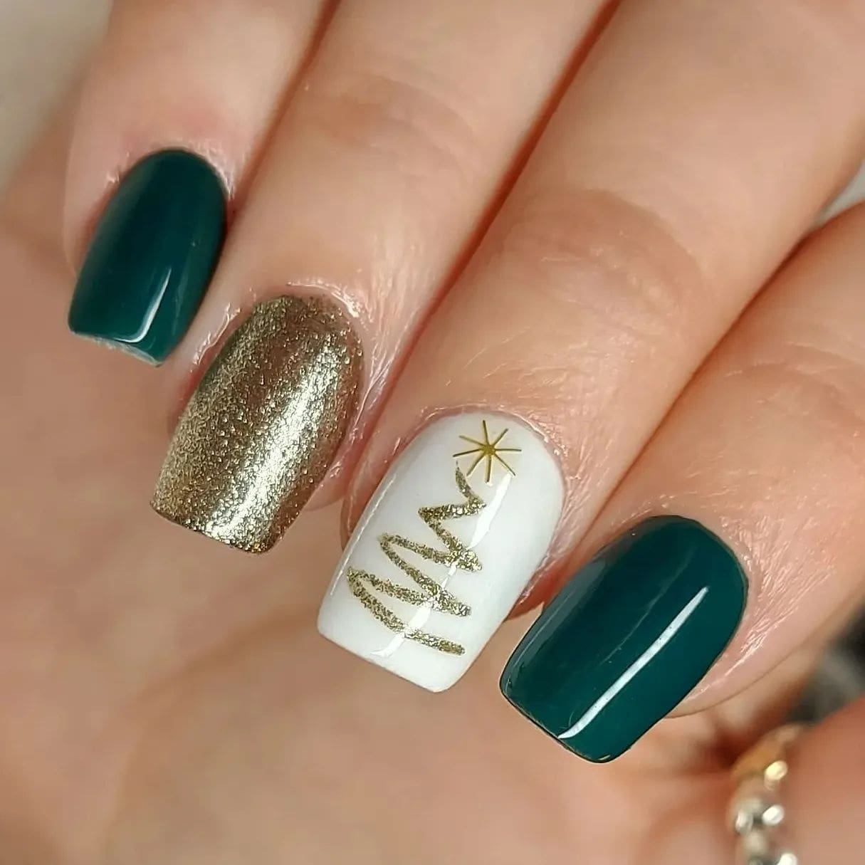 Eine Nahaufnahme von Nägeln in festlicher Kombination aus Grün, Weiß und Gold
