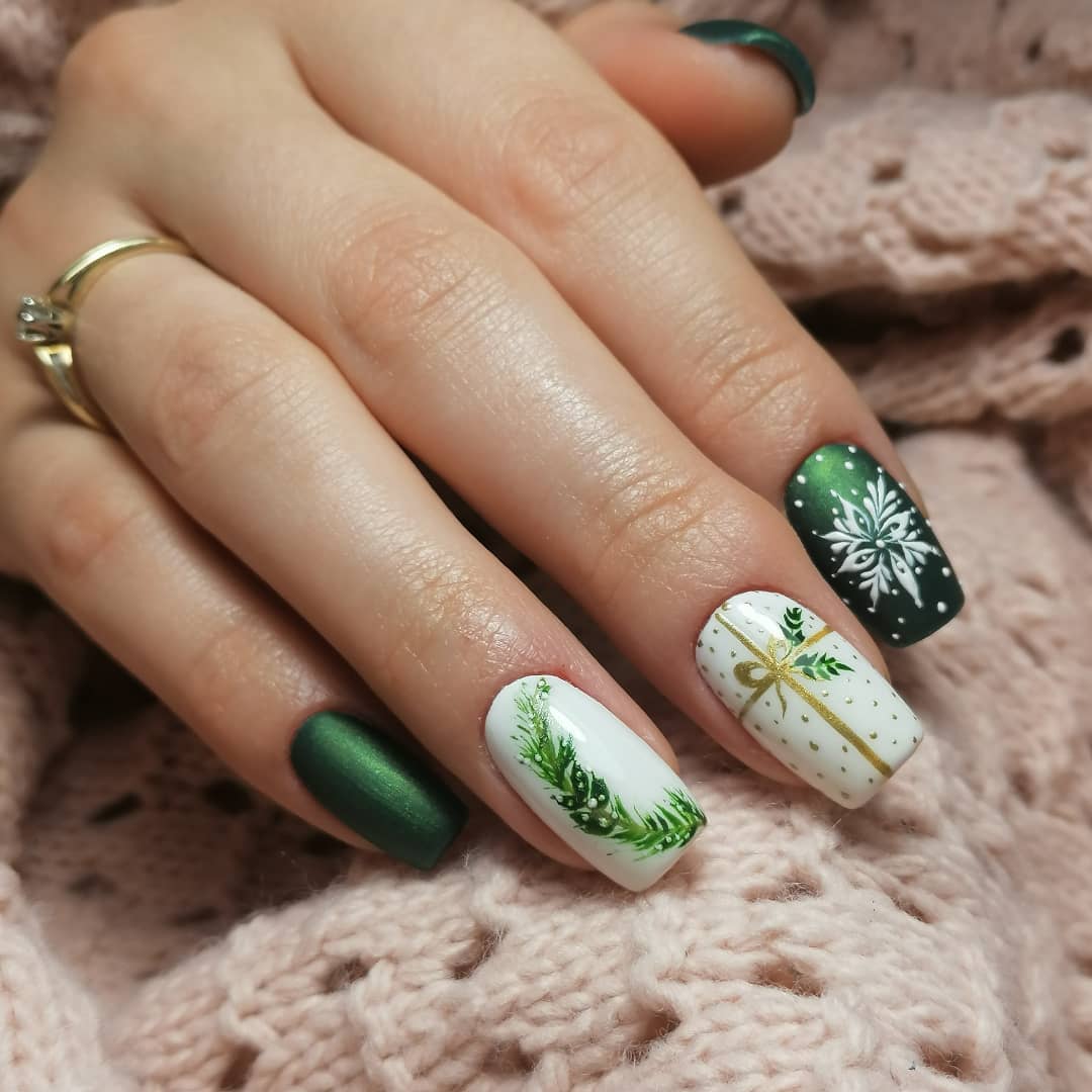 Eine Nahaufnahme dunkelgrüner und weißer Nägel mit Wintergemälden