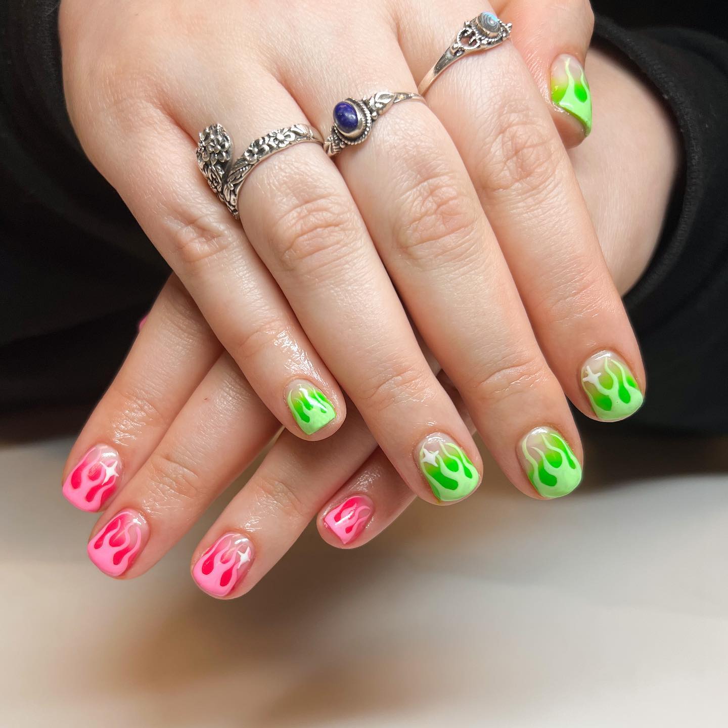 Eine Nahaufnahme von Nägeln mit süßen französischen Spitzen in rosa und grünen Farben