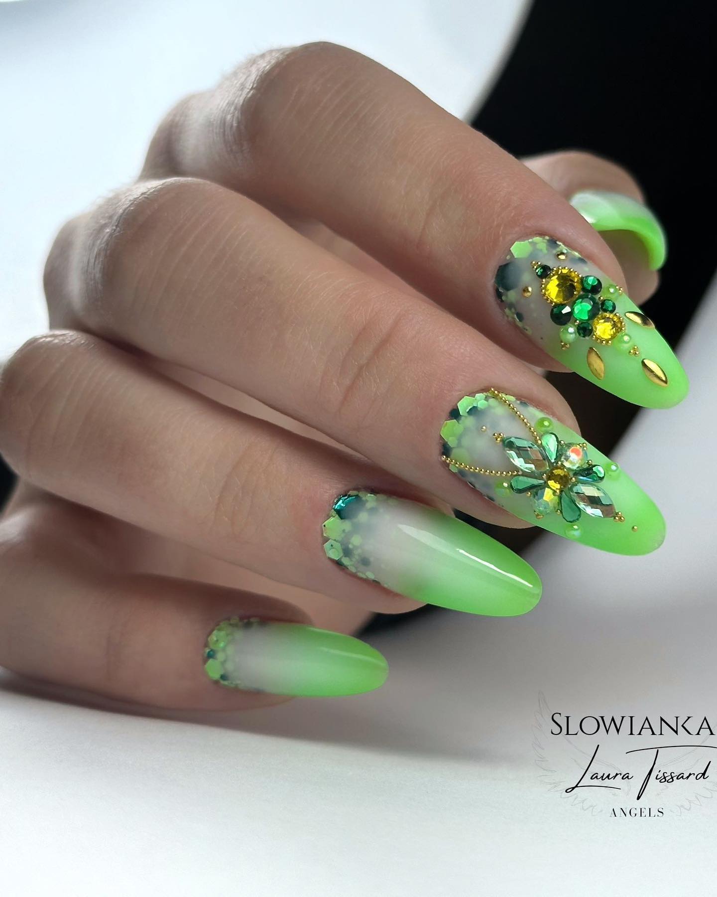 Eine Nahaufnahme von lindgrünen Ombre-Nägeln mit Glitzer und Diamanten