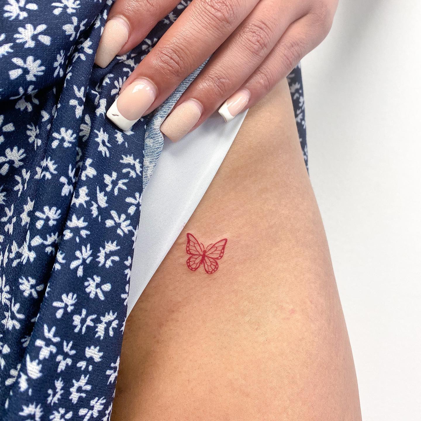 Kleines rotes Schmetterlings-Tattoo auf dem Oberschenkel
