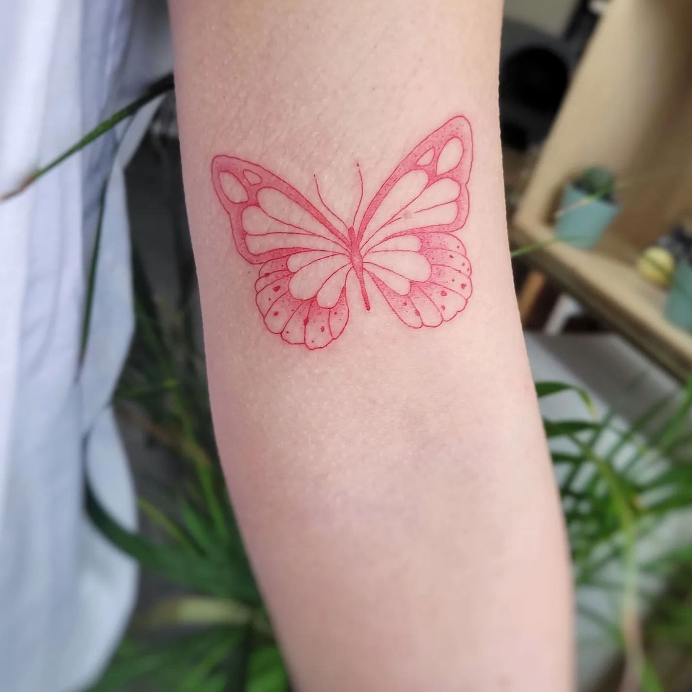 Red butterfly tattoo on forearm