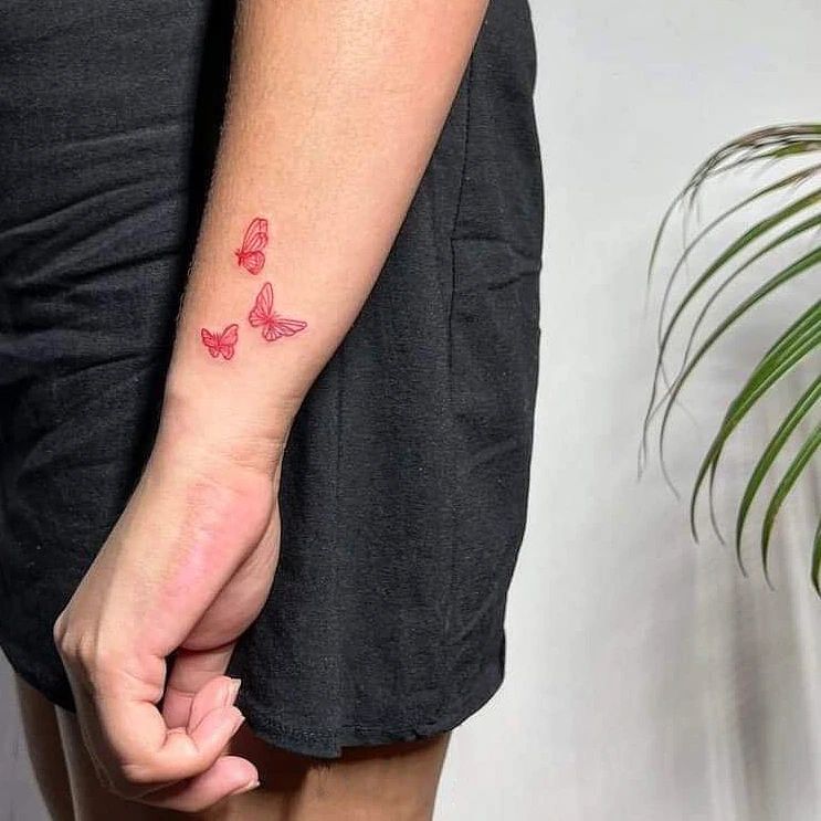 Tattoo mit drei fliegenden Schmetterlingen am Handgelenk