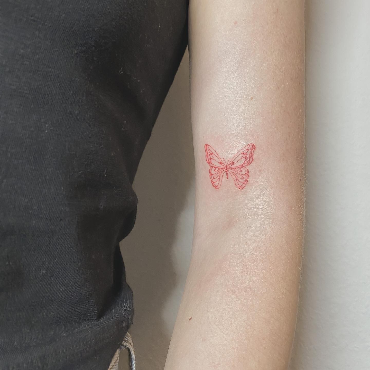 Ein rotes Schmetterlingstattoo auf dem Arm