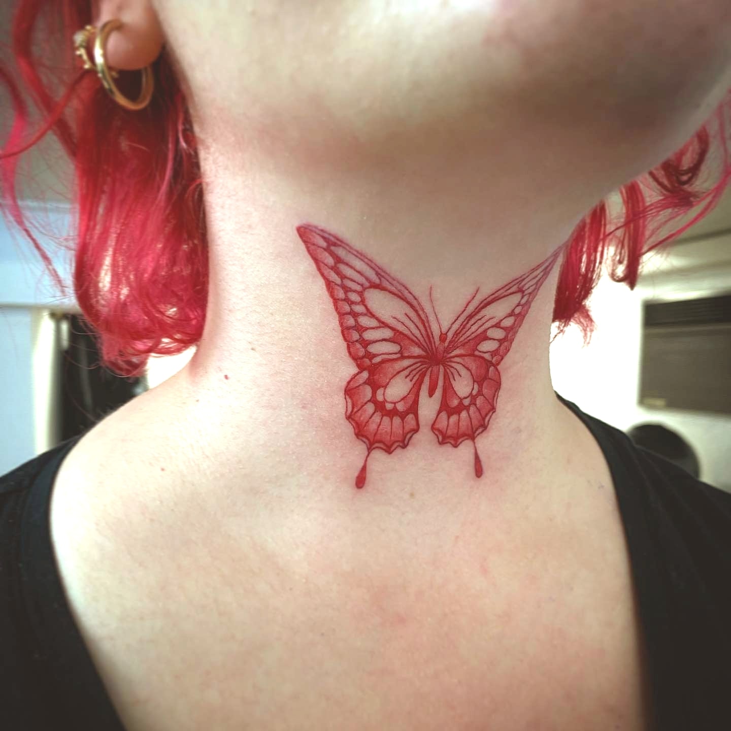 Duży czerwony tatuaż motyla na szyi