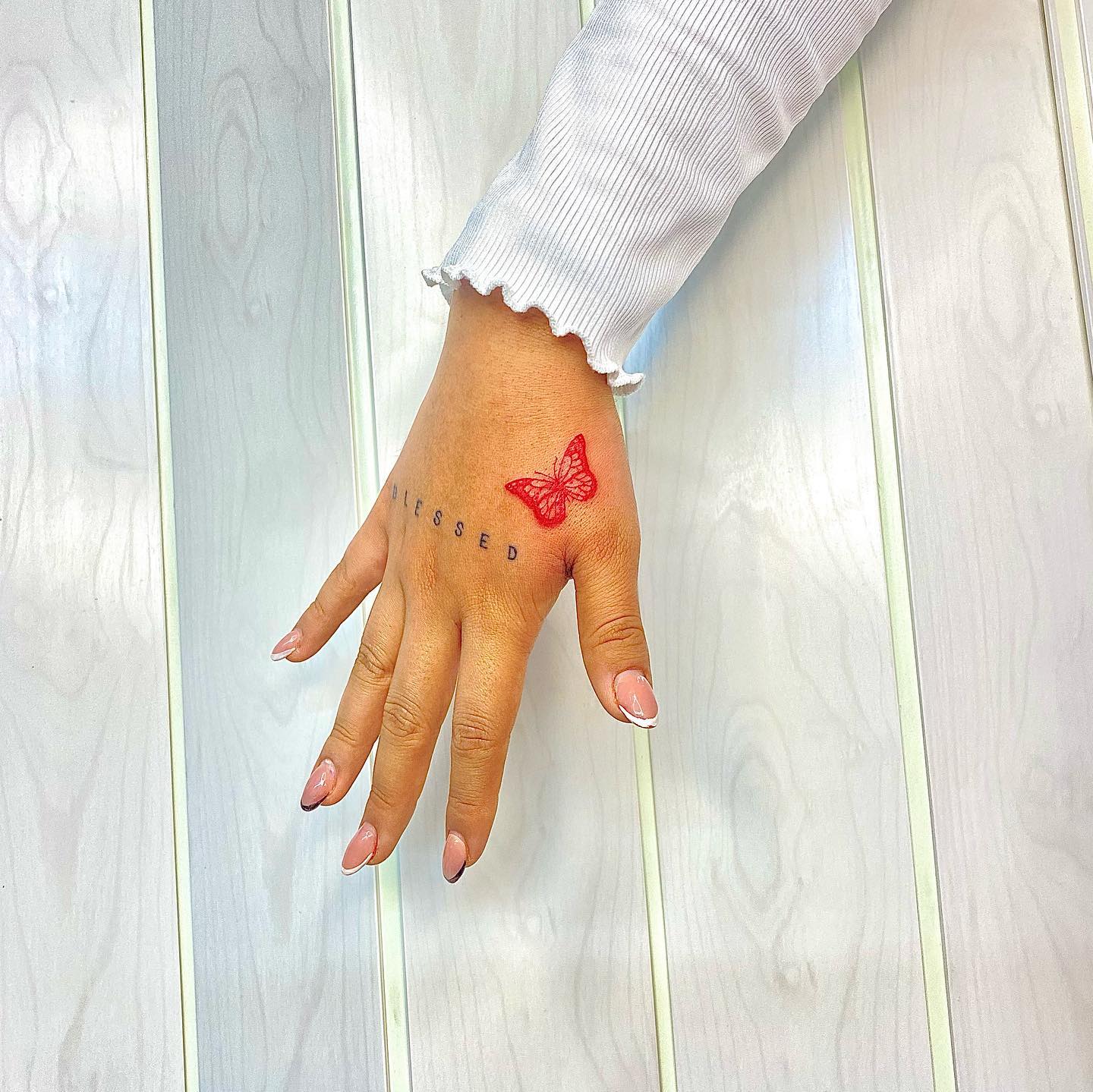 Small red butterfly tattoo on hand