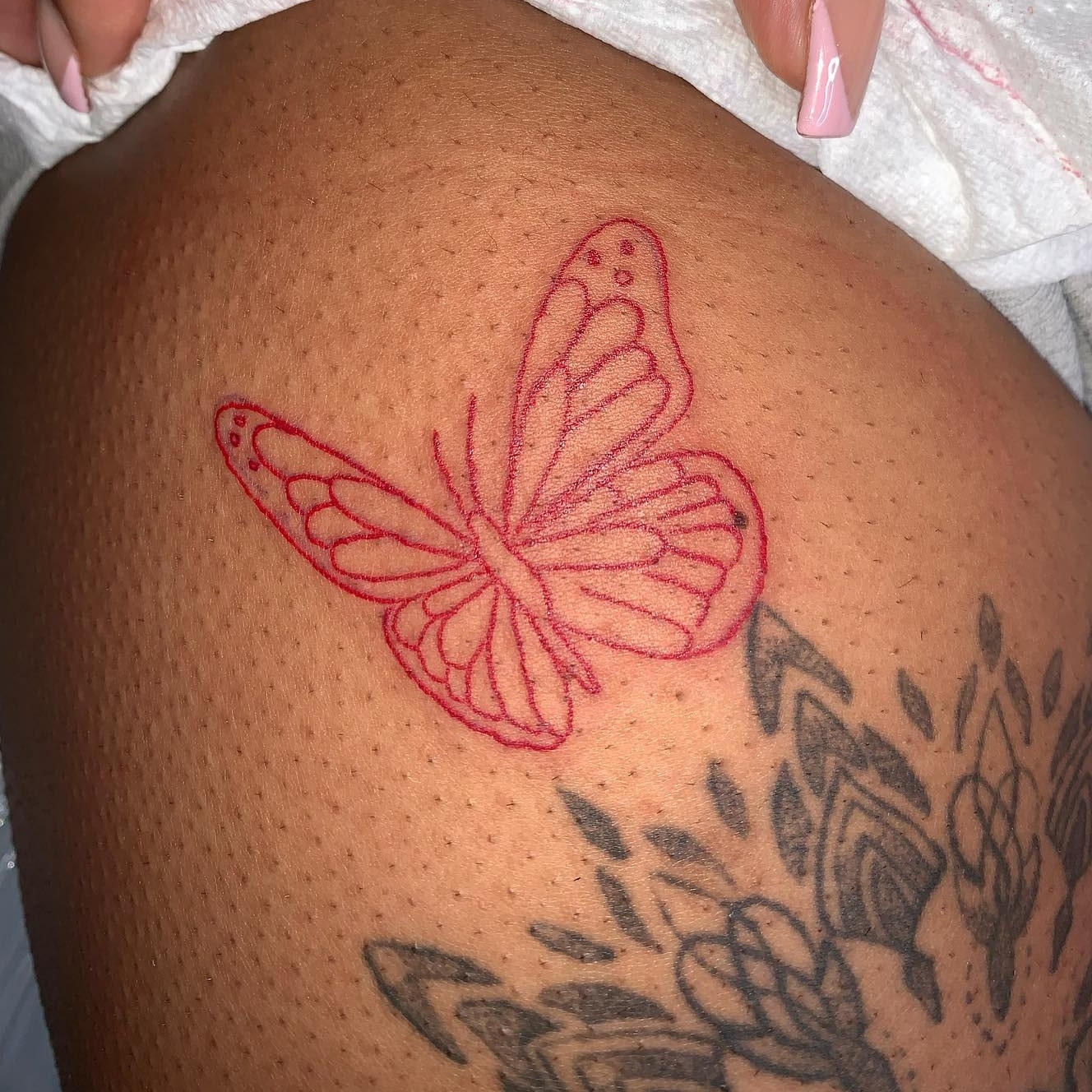 Red butterfly tattoo on black skin