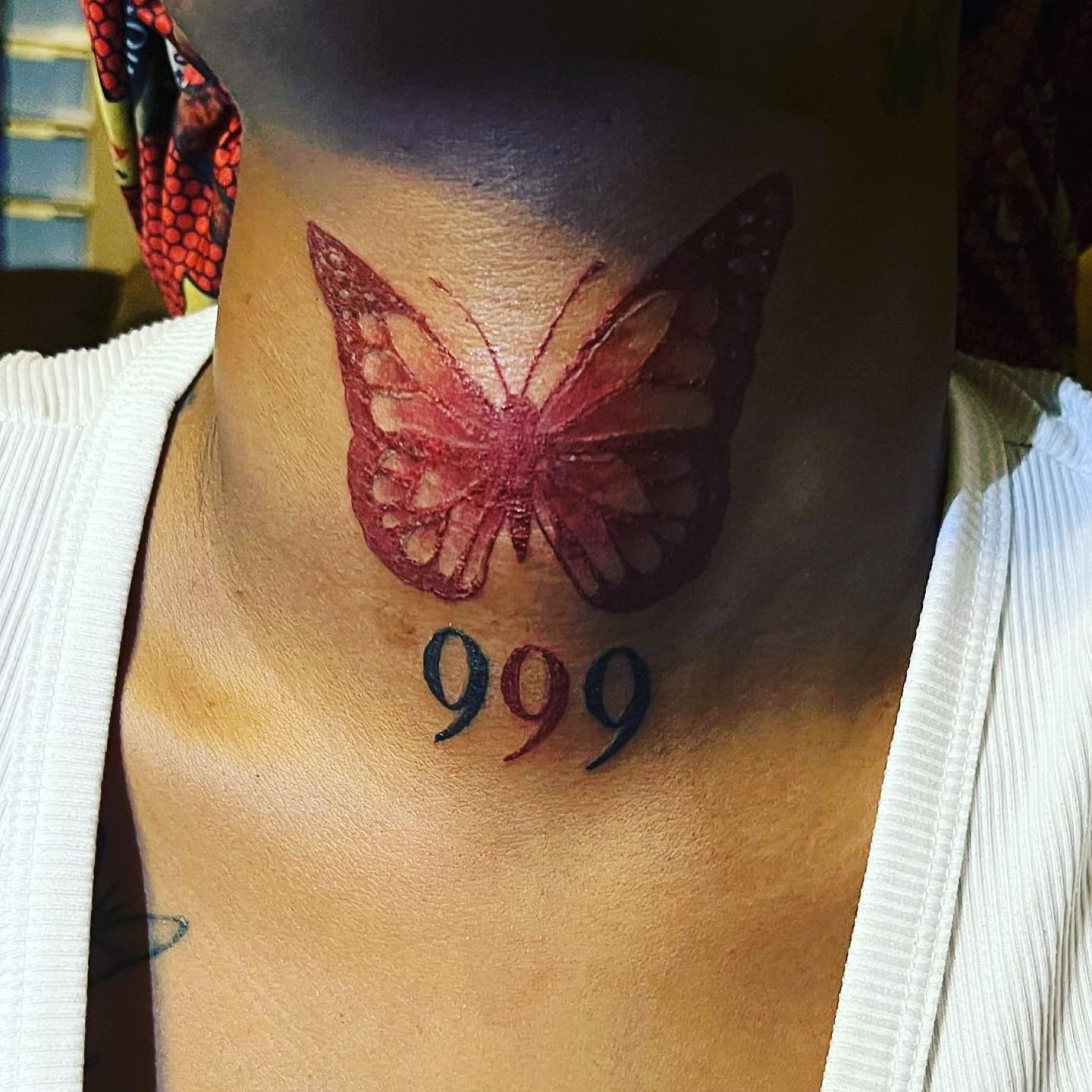 Яркая красная татуировка бабочки на шее