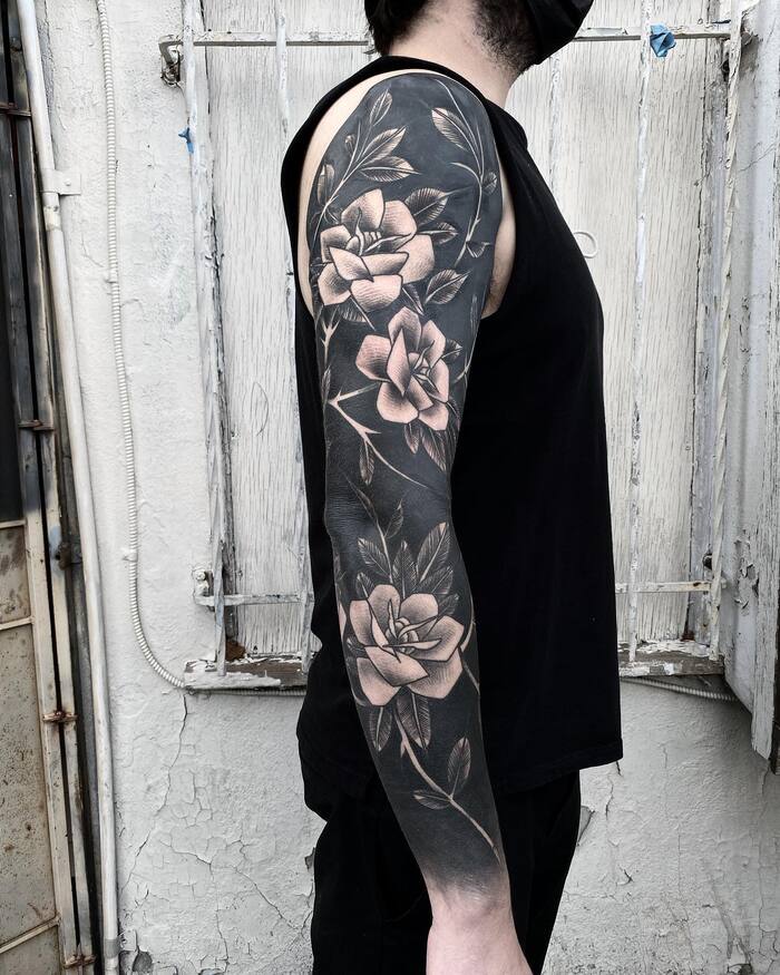Blackout negative space sleeve tattoo with rose flowers