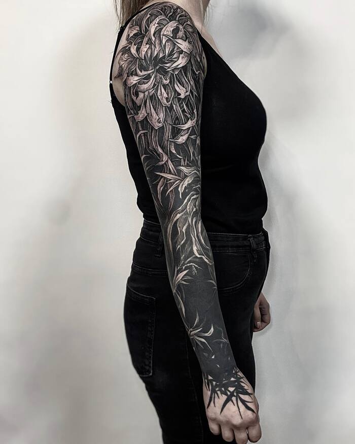 Female peony blossom blackout sleeve tattoo