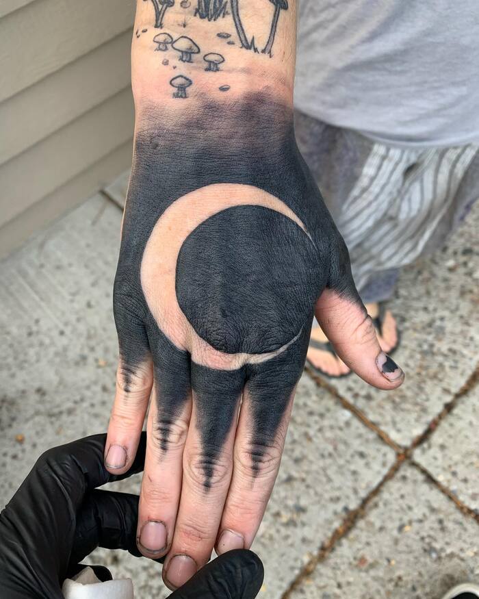 Blackout moon tattoo on hand 