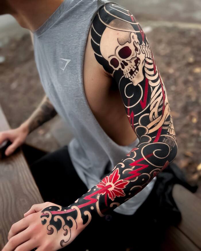 Blackout skull sleeve tattoo with red and white inks