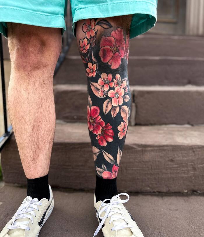 Sakura blossom blackout leg tattoo with pink inks