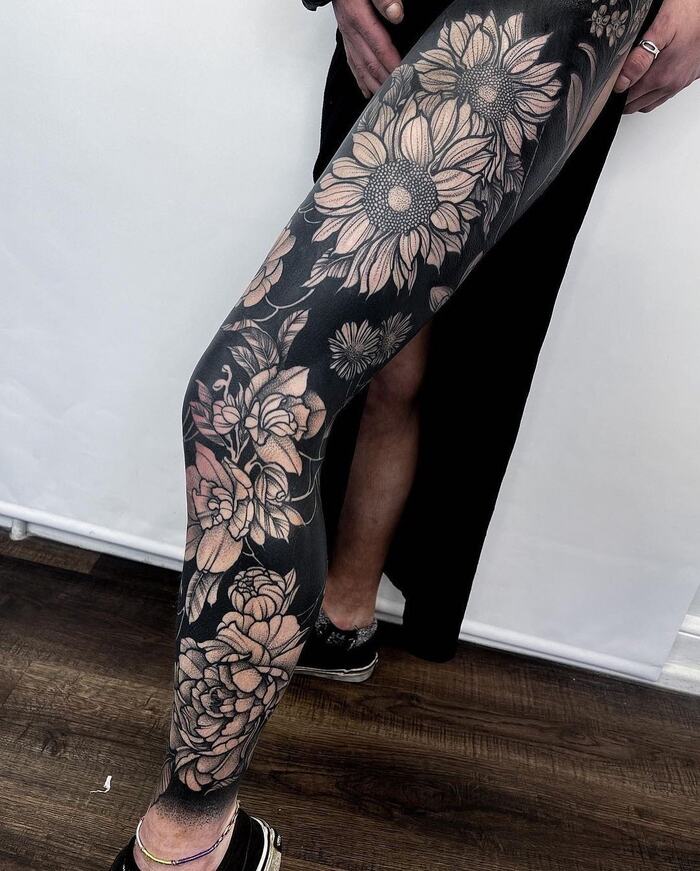 Female blackout sunflower tattoo on leg