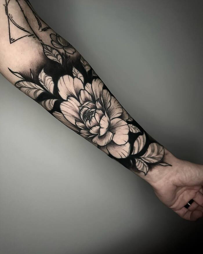 Blackout negative space flower forearm tattoo