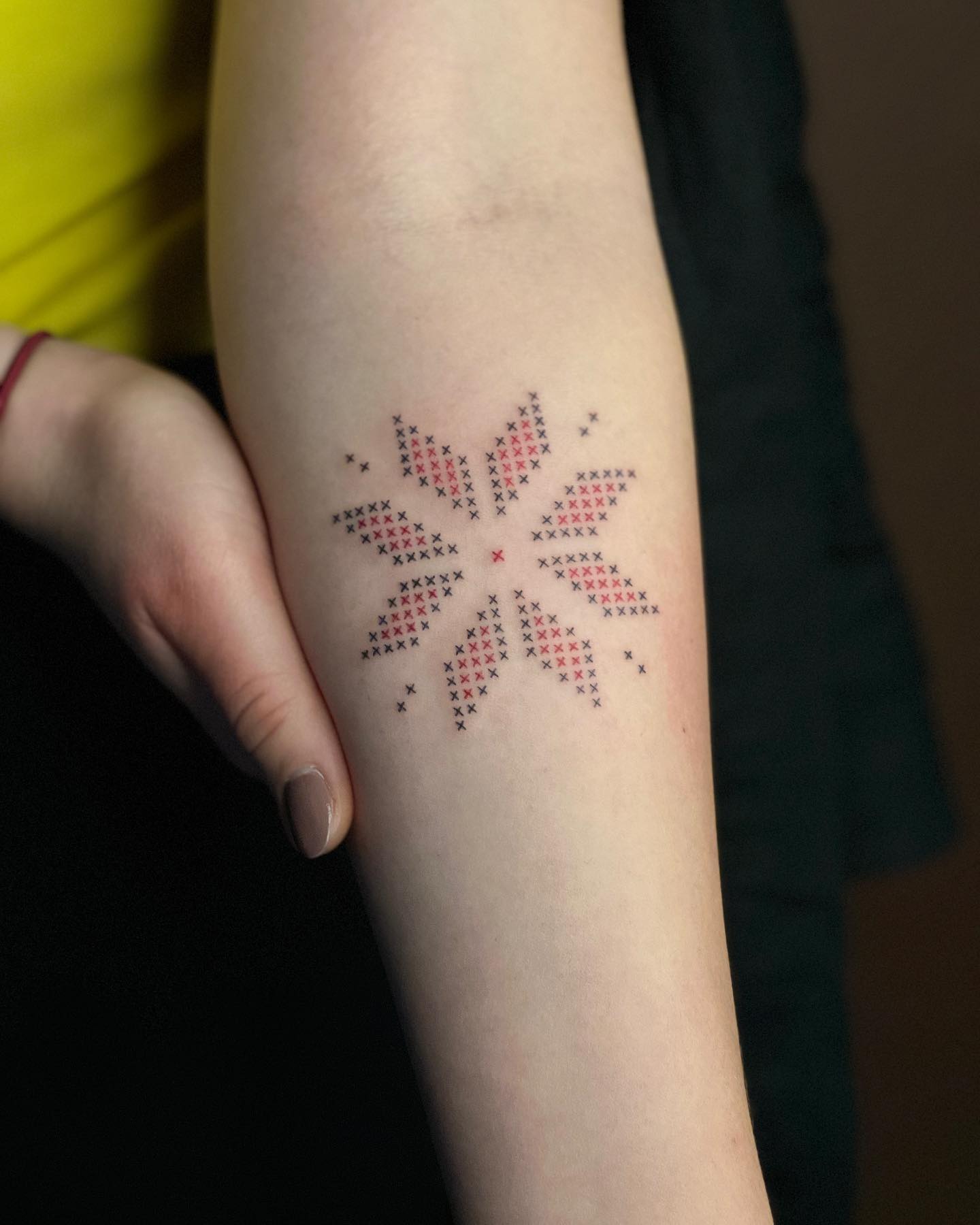 Kleines gesticktes Kreuz-Tattoo einer Blume in Schwarz und Rot