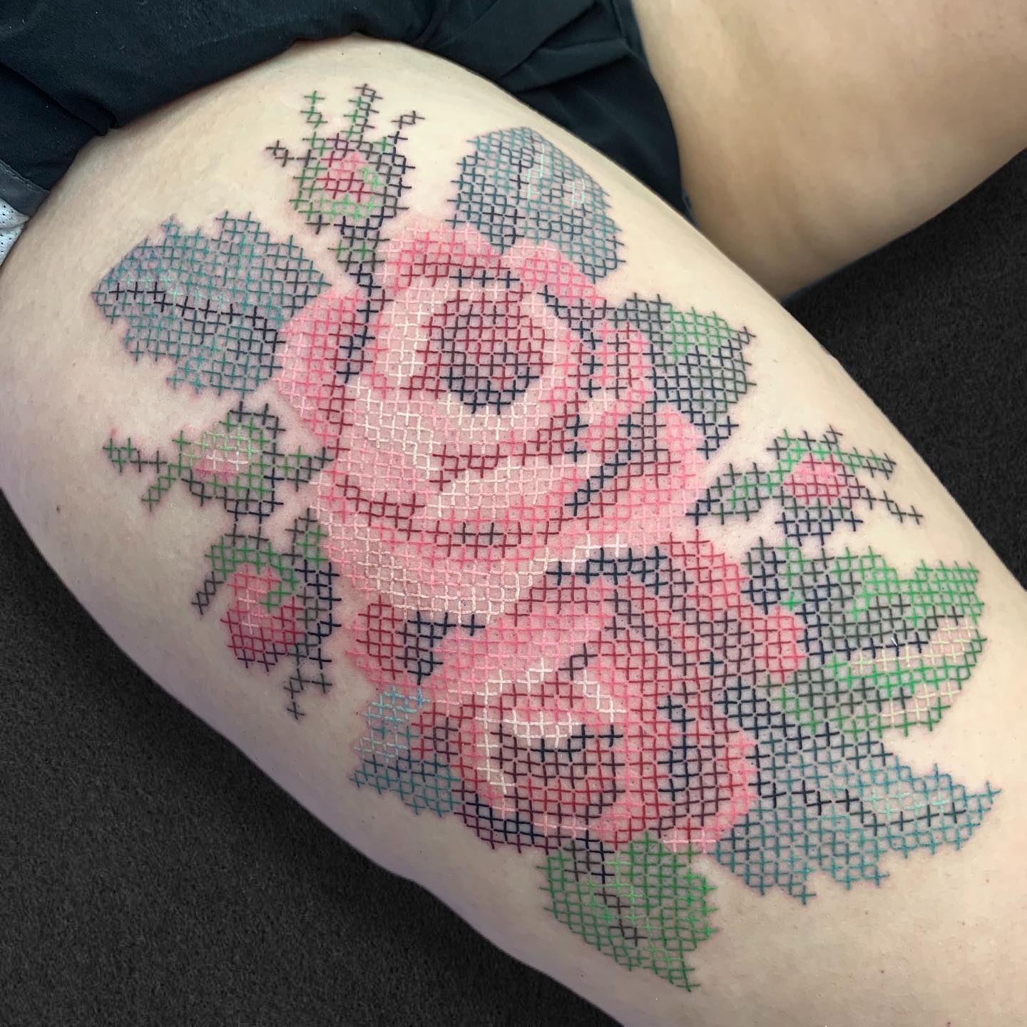 Tattoo mit aufgesticktem Rosenstrauß auf dem Oberschenkel