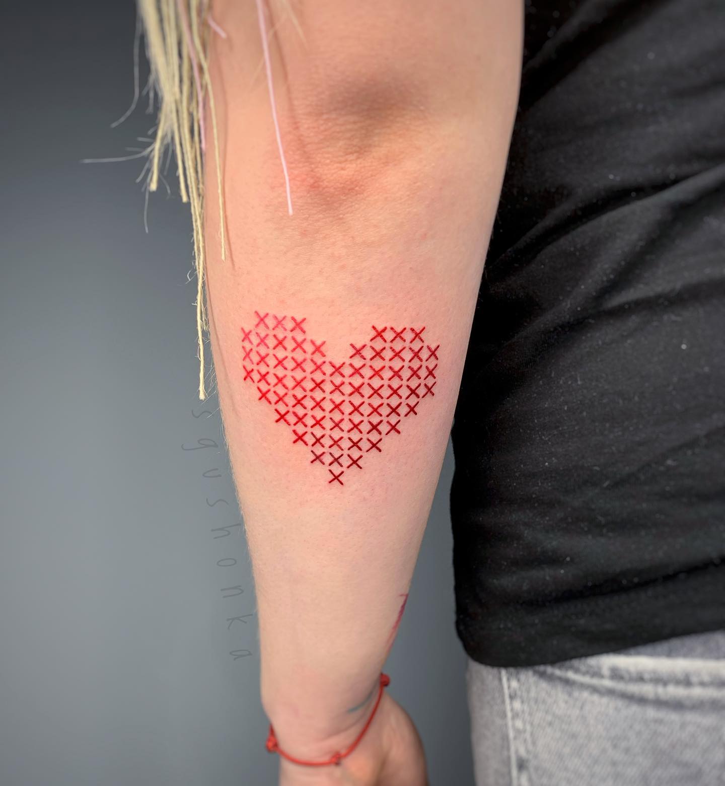 Tatuaż z haftem serca w technice krzyżowej