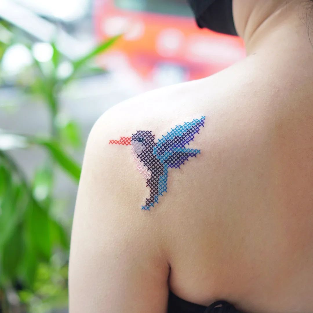 Mały haftowany tatuaż kolibra w technice krzyżowej