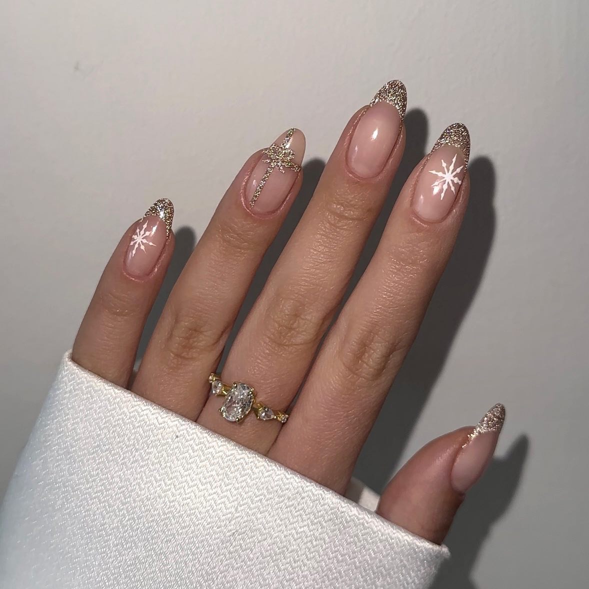 Gold Glitter French Tip Nails on neutral base with snowflakes on main finger