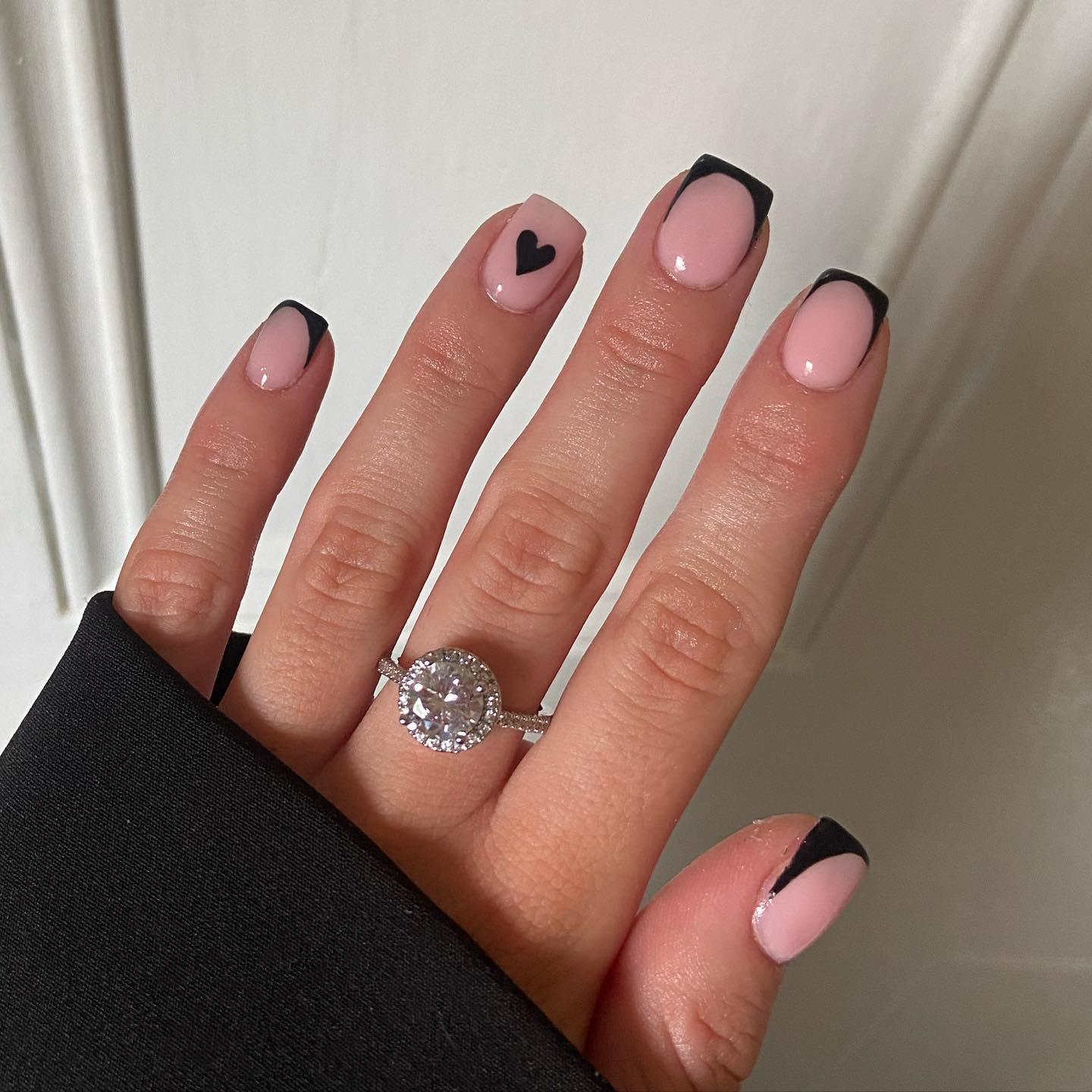 short square nails with neutral base, black french tips and small black heart on ring finger