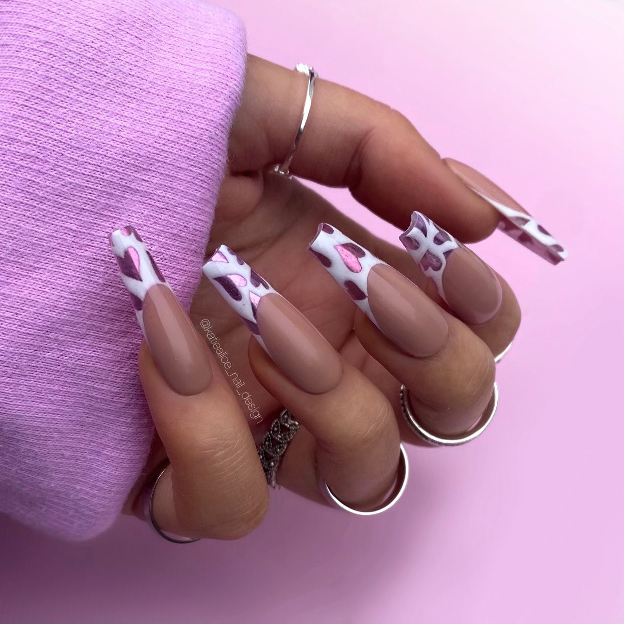 French nails with brown base and white tips with chrome purple hearts on it