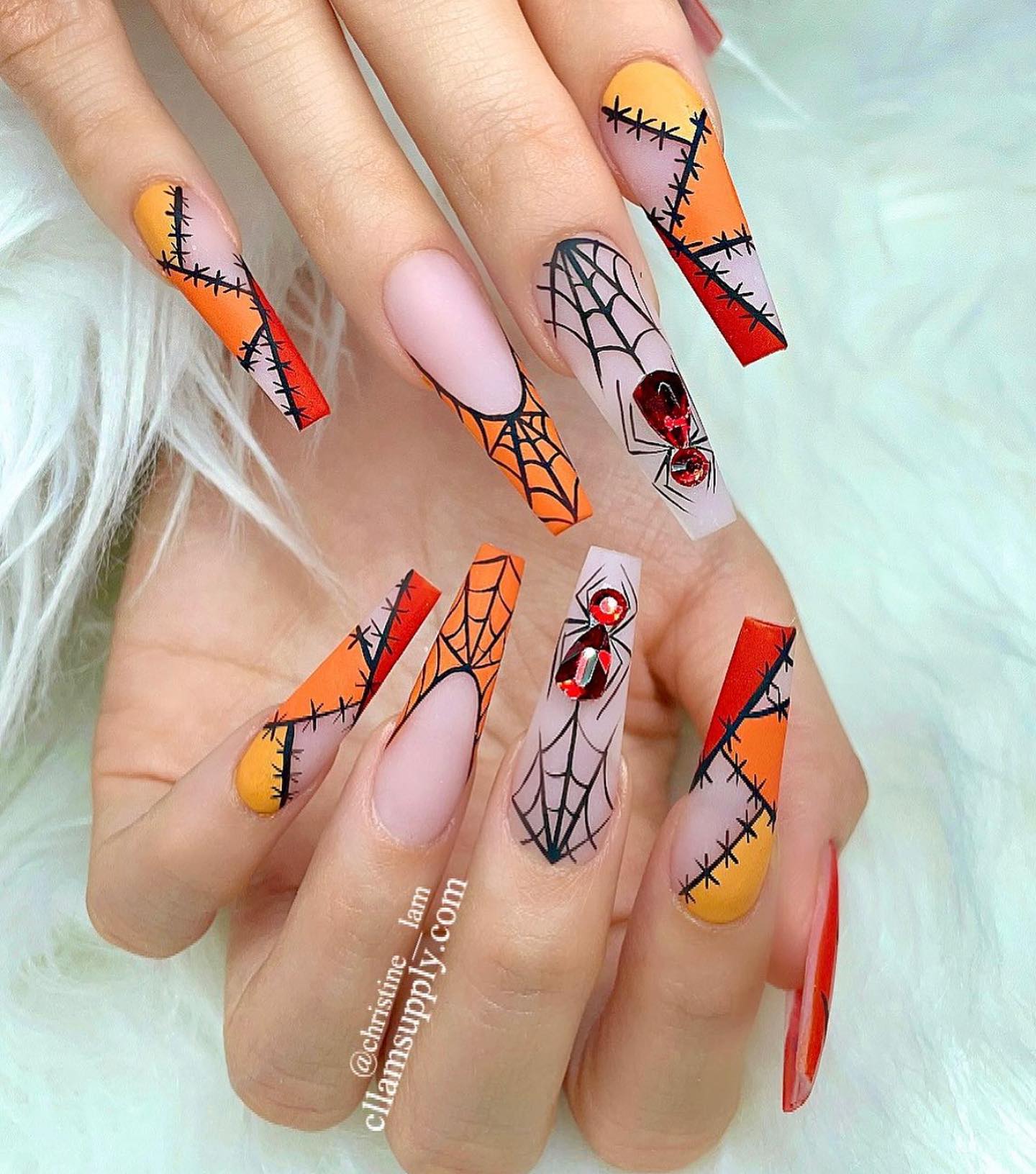 Długie, wciskane paznokcie pomalowane w Halloweenowe historie, w kombinacji kolorów czerni i pomarańczy