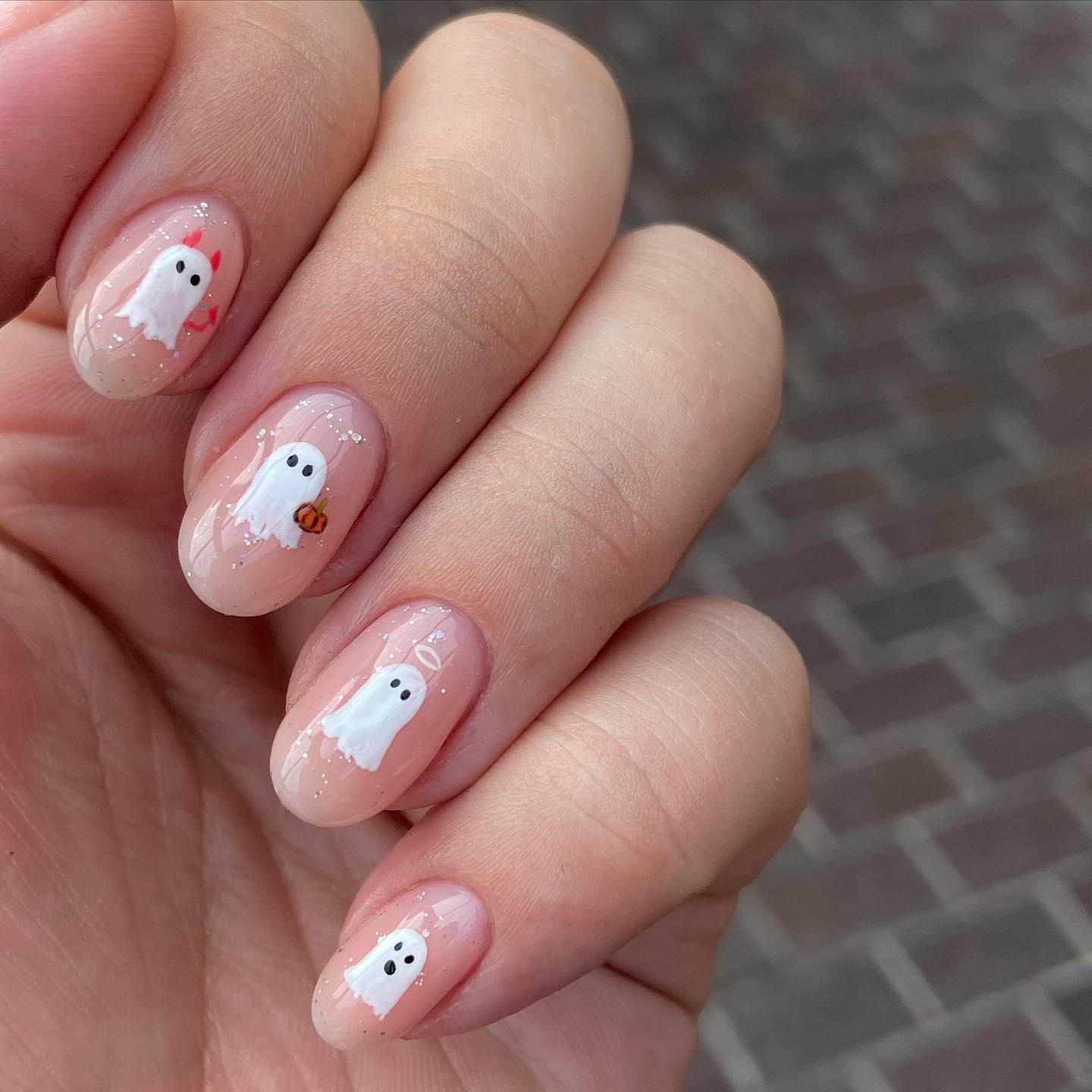 Halloween manicure with cute white ghosts on light nude base