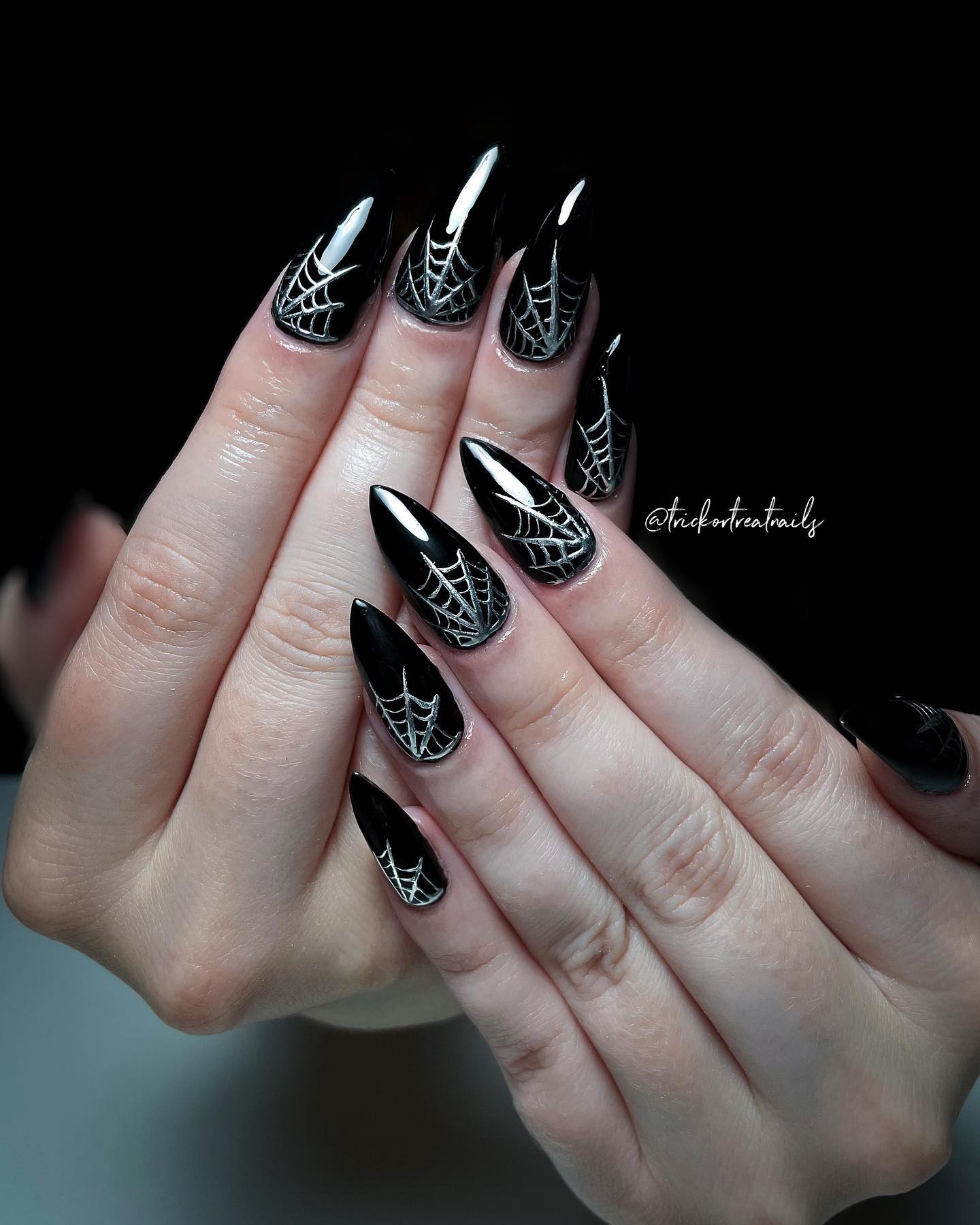 Another example of white or silver spider web in glossy black almond or coffin shaped nails