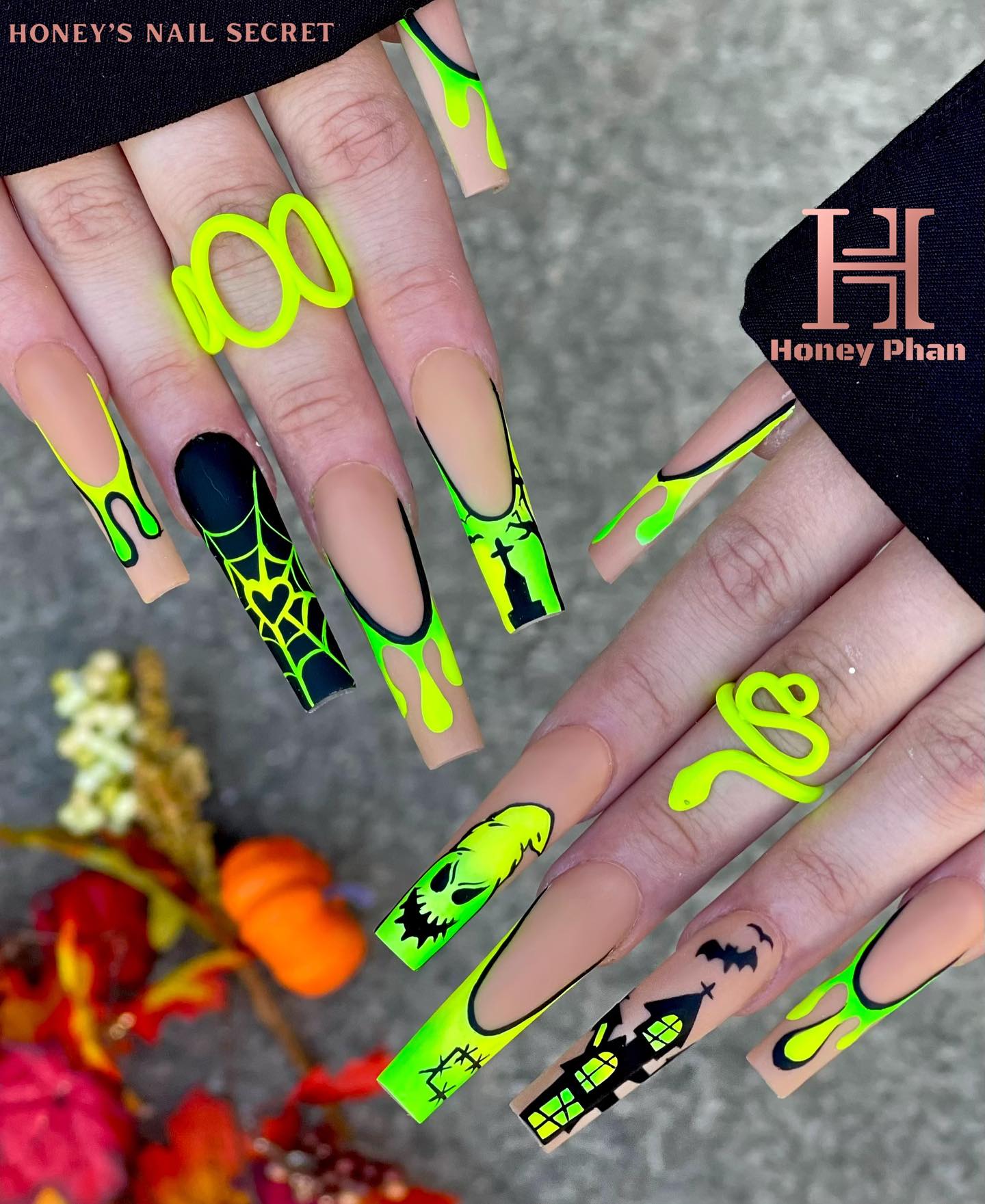 Halloween nail art with themed paintings and neon green accents