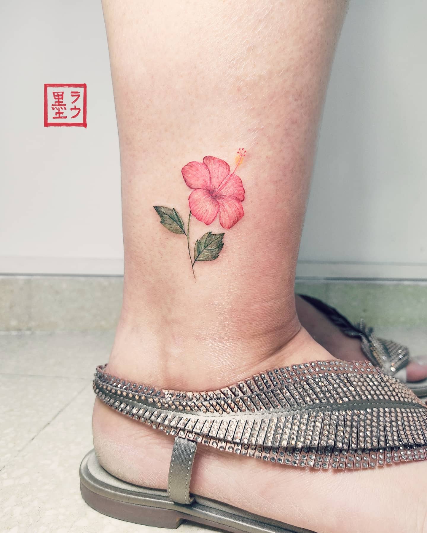 Hawajski tatuaż z małym kwiatkiem na nodze