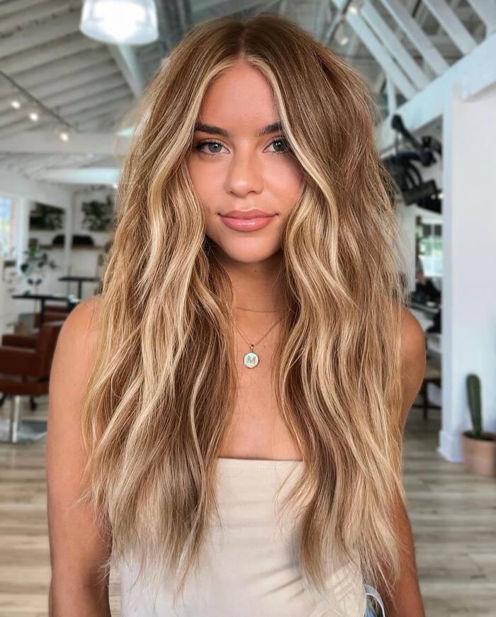 Young girl with long layered locs in warm honey blonde color