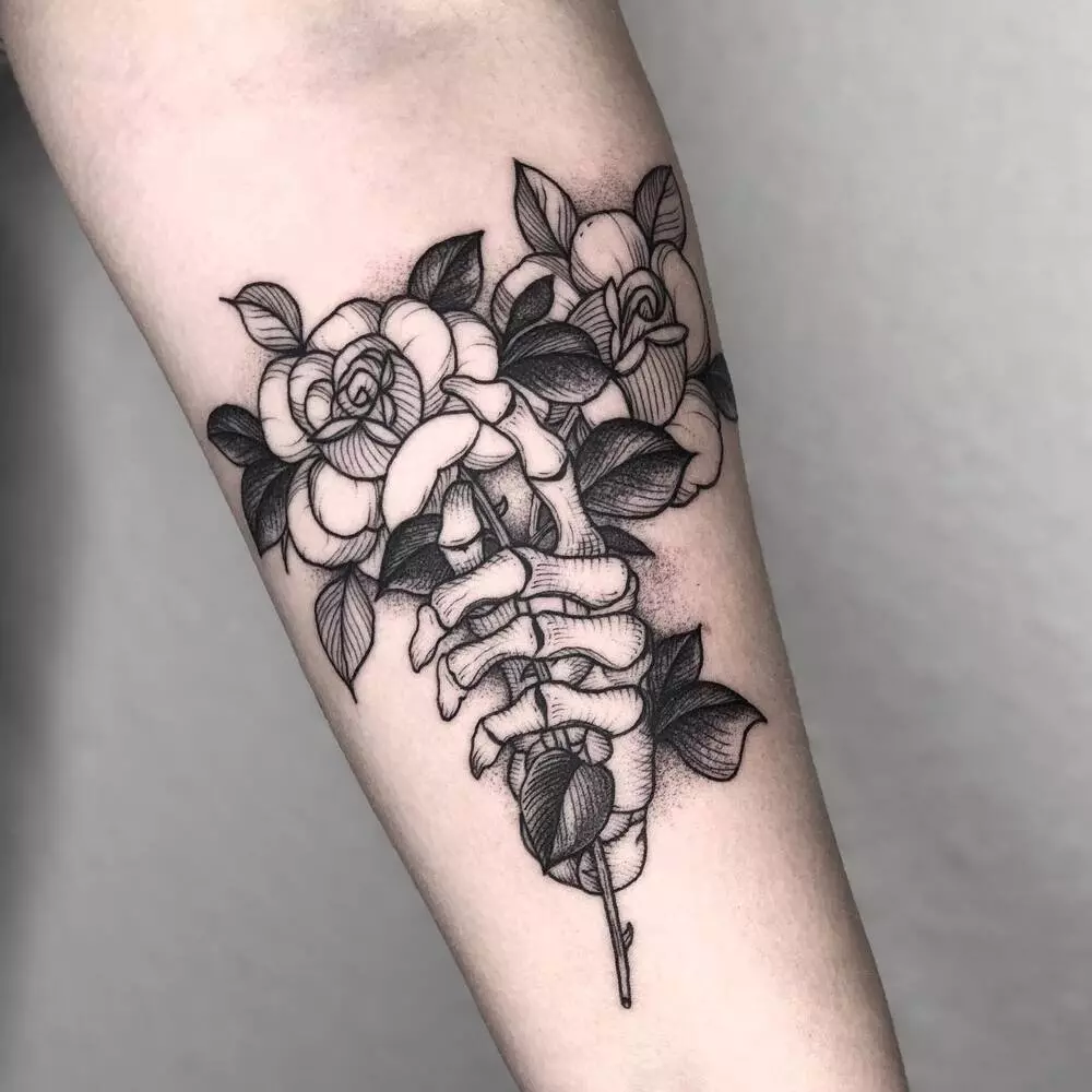 A Close-up Image of Skeleton Hand Holding Two White Roses Tattoo