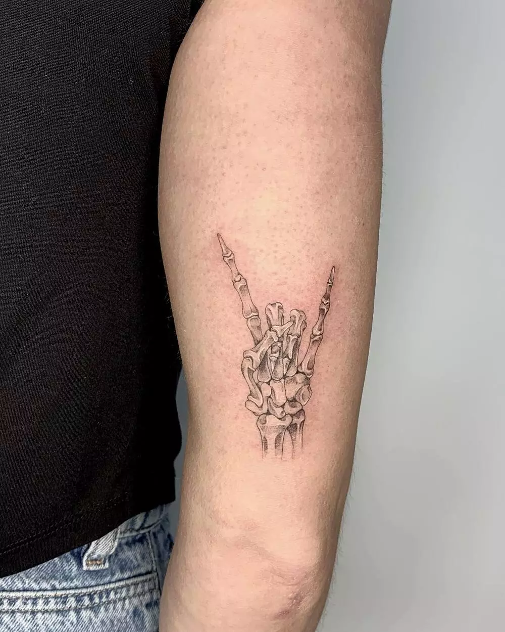 A Close-up Image of Small Skeleton Rock On Hand Tattoo on Arm
