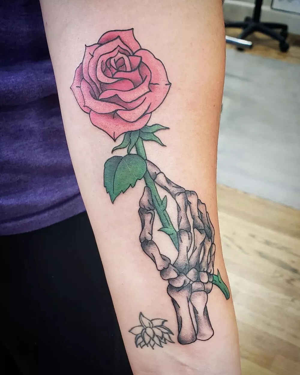 A Close-up Image of Black Skeleton Hand Holding Red Rose Tattoo