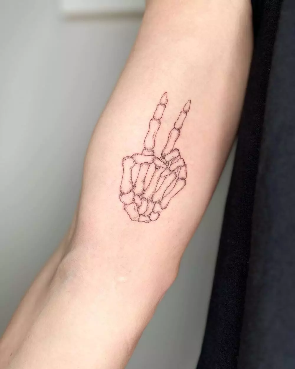 A Close-up Image of Skeleton Hand Showing Peace Sign Tattoo