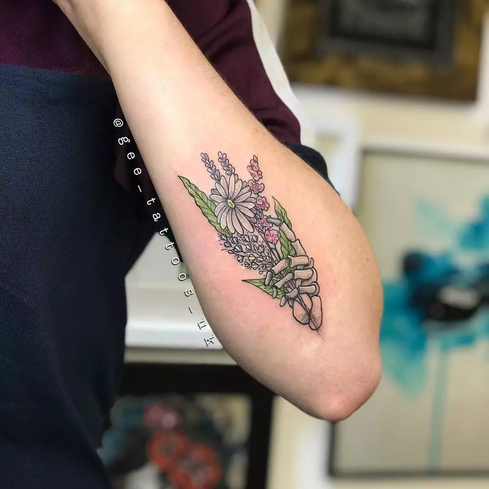 A Close-up Image of Colorful Skeleton Hand Holding Wildflowers Tattoo