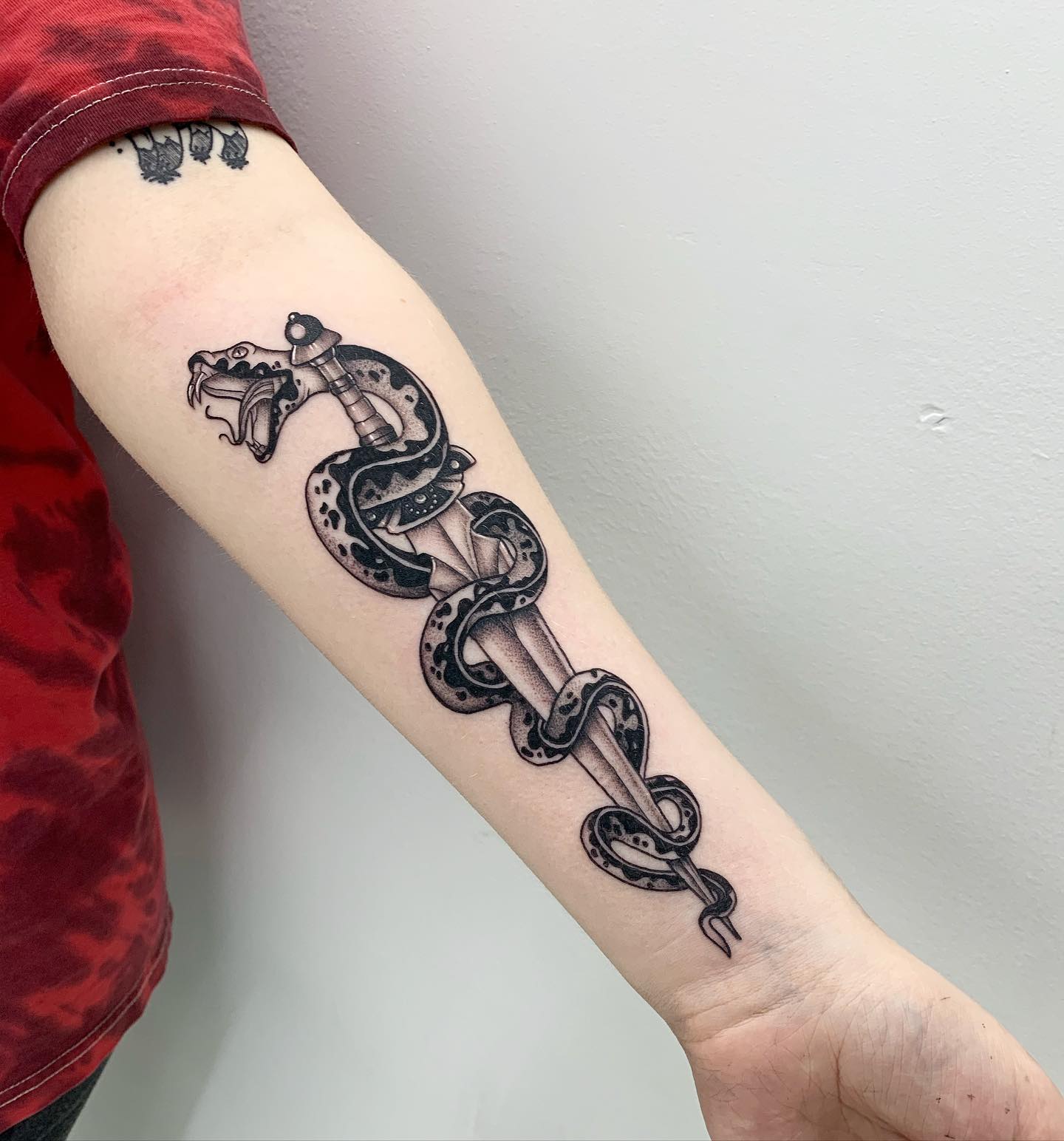 Nahaufnahme des Schlangen- und Dolch-Tattoos in Schwarz und Grau