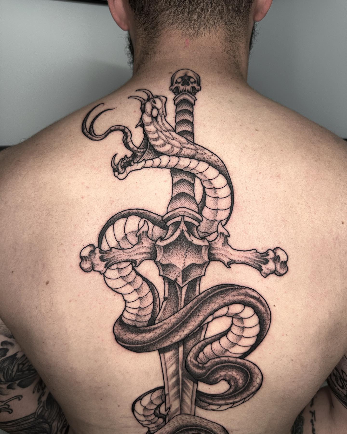 Nahaufnahme des Klapperschlangen- und Schwert-Tattoos